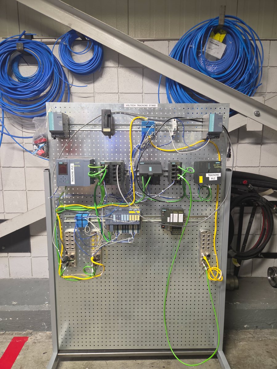 PLC training stand with Siemens PLCs, network switches, and remote I/O on a pegboard